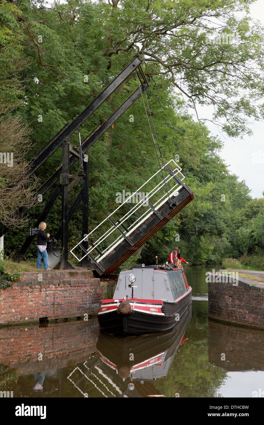 A narrowboat passing under the raised drawbridge at Hockley Heath on the Stratford on Avon Canal Stock Photo