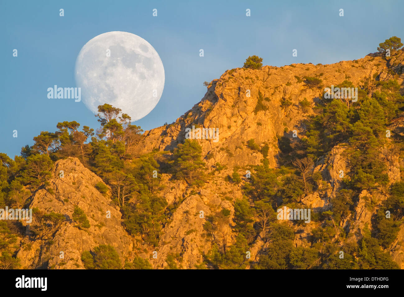 Real full moon rising over Puig des Teix mountain at sunset. Tramuntana mountains, Deià, Majorca, Balearic islands, Spain Stock Photo