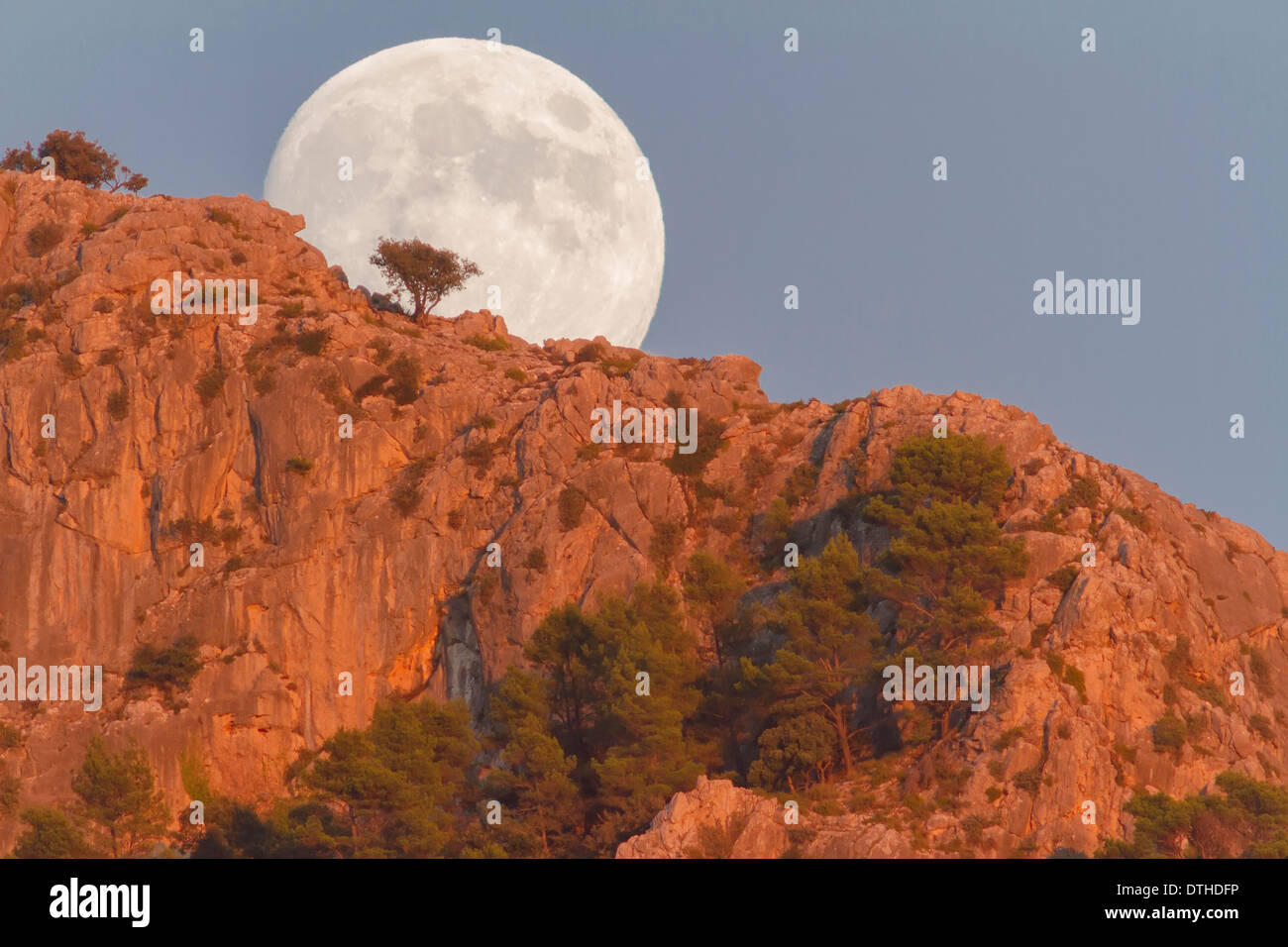 Real full moon rising over Puig des Teix mountain at sunset. Tramuntana mountains, Deià, Majorca, Balearic islands, Spain Stock Photo