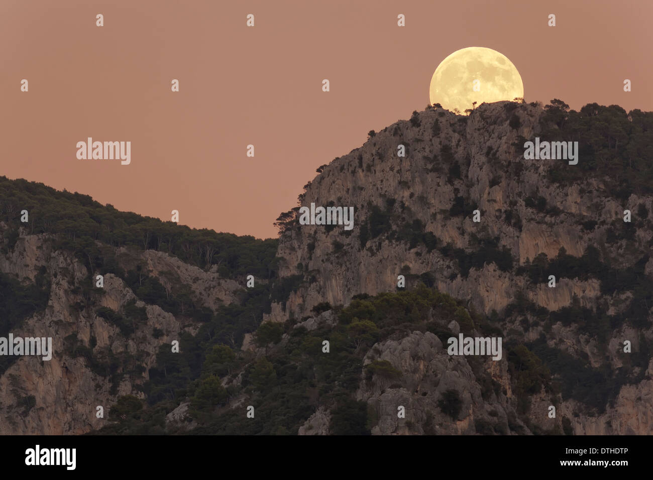 Real full moon rising over Penyal d'Honor mountain at dusk. Tramuntana hills, Bunyola area, Majorca, Balearic islands, Spain Stock Photo