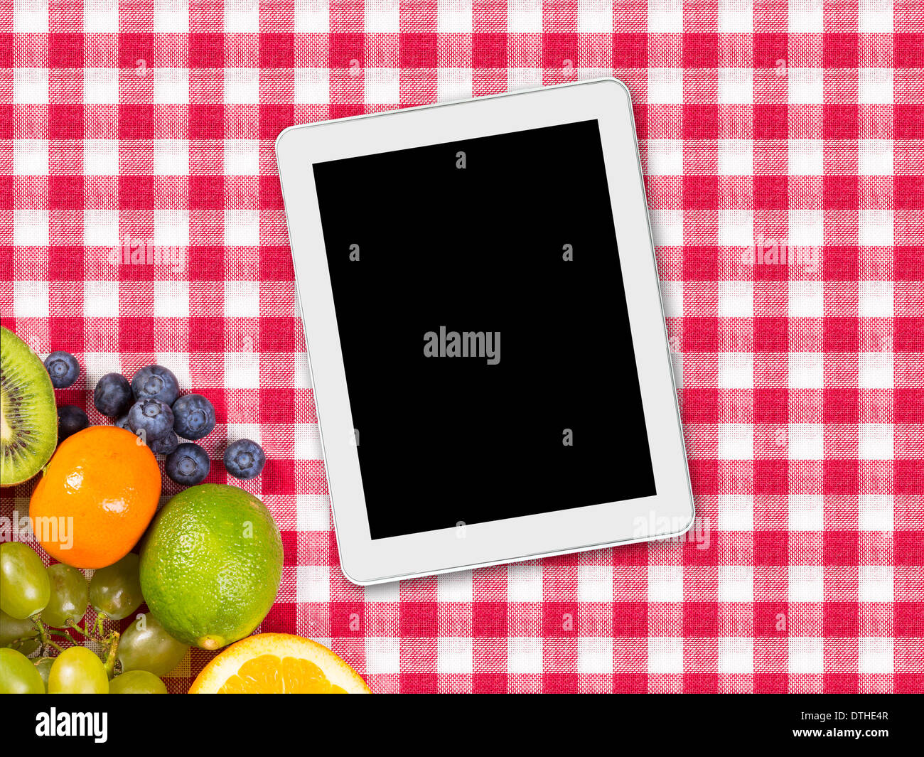 tablet and fruit on tablecloth textile Stock Photo