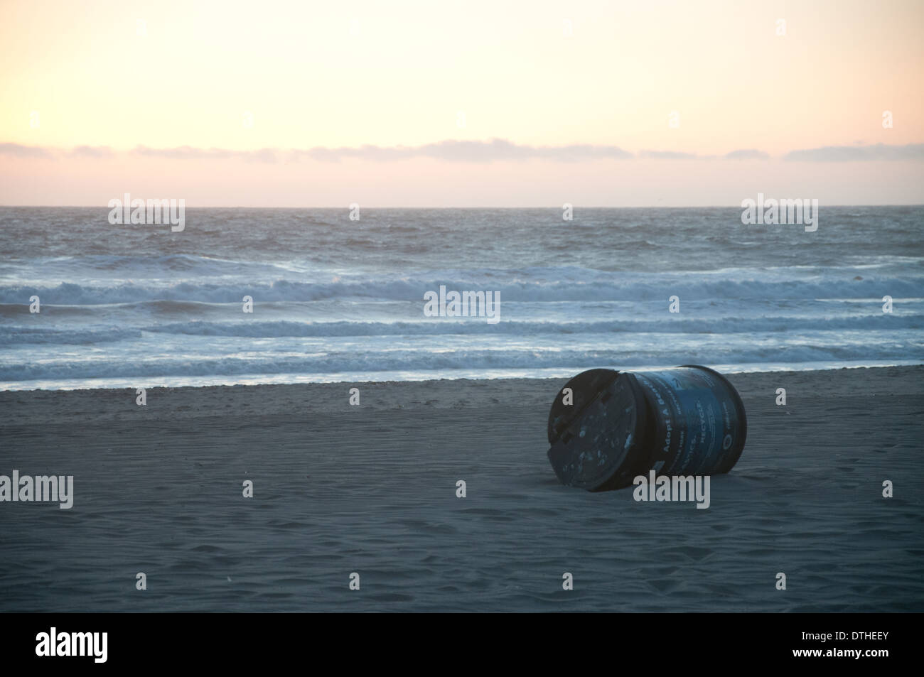 An empty metal drum on the beach at sunset Stock Photo