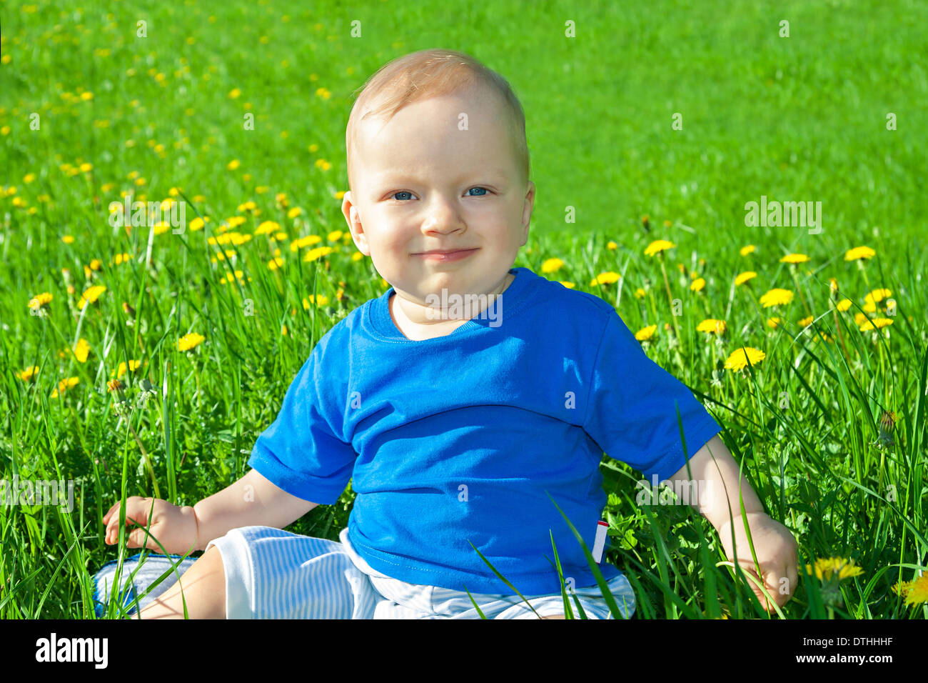 the beautiful small child the boy plays on a green meadow Stock Photo