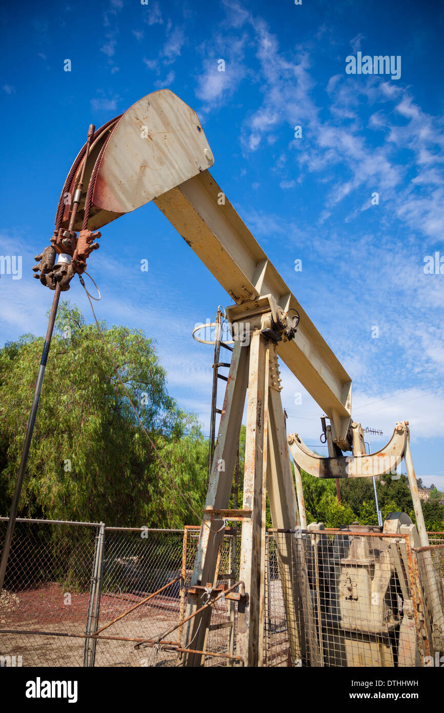 A horsehead pumpjack with a blue sky background with clouds Stock Photo