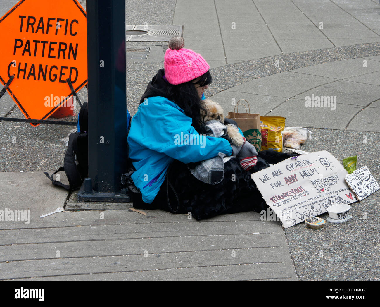 Young homeless woman hugging her dog sitting on the sidewalk in downtown Vancouver, BC, Canada Stock Photo
