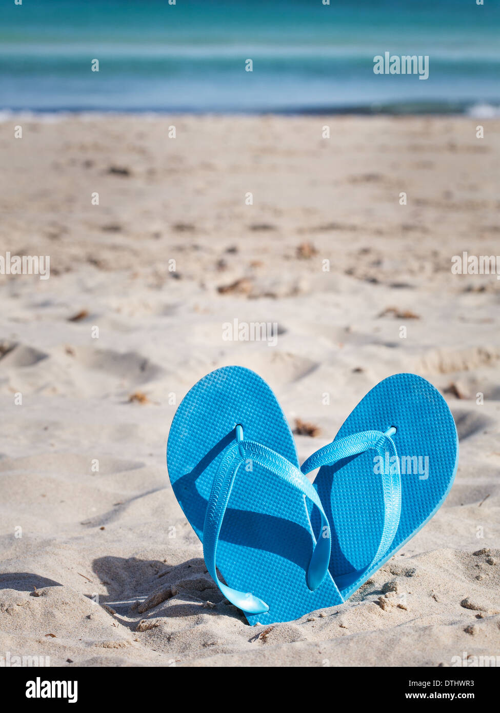 Pair of blue flip flops on sand beach Stock Photo - Alamy