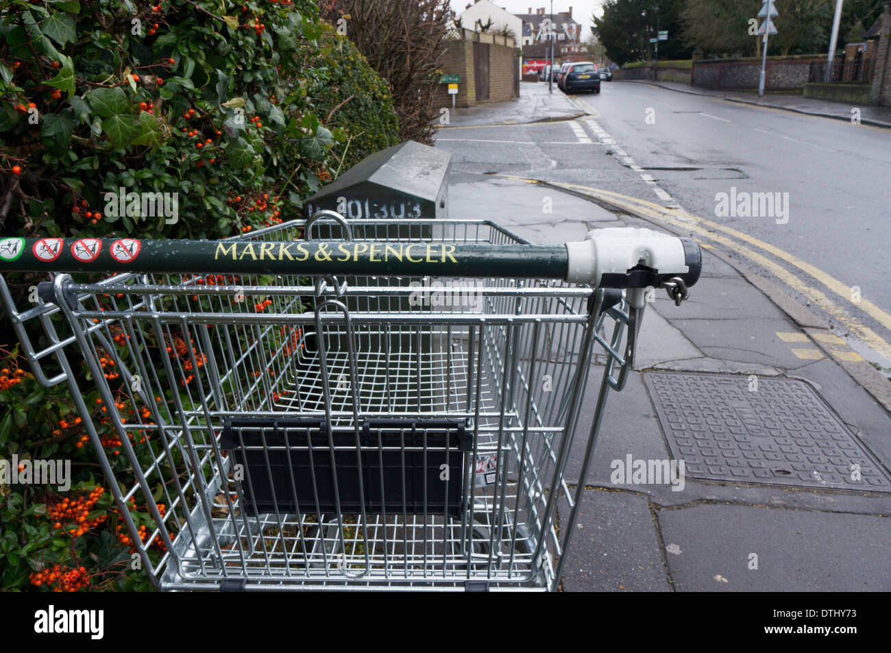 An abandoned Marks & Spencer trolley on the pavement of a quiet suburban street. Stock Photo
