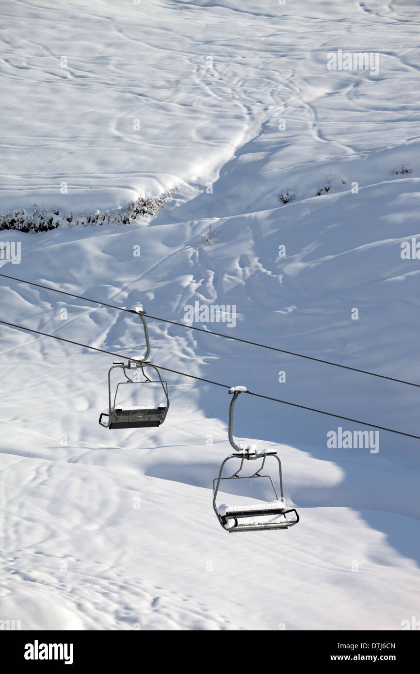 Two chairlift with snowdrift and offpiste slope in sun morning