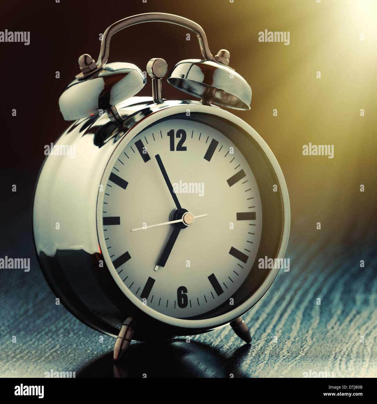 metallic Alarm clock on bedside table in morning light Stock Photo