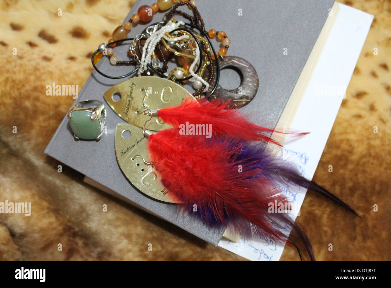 book on fur with ring, earrings from colorful feathers Stock Photo