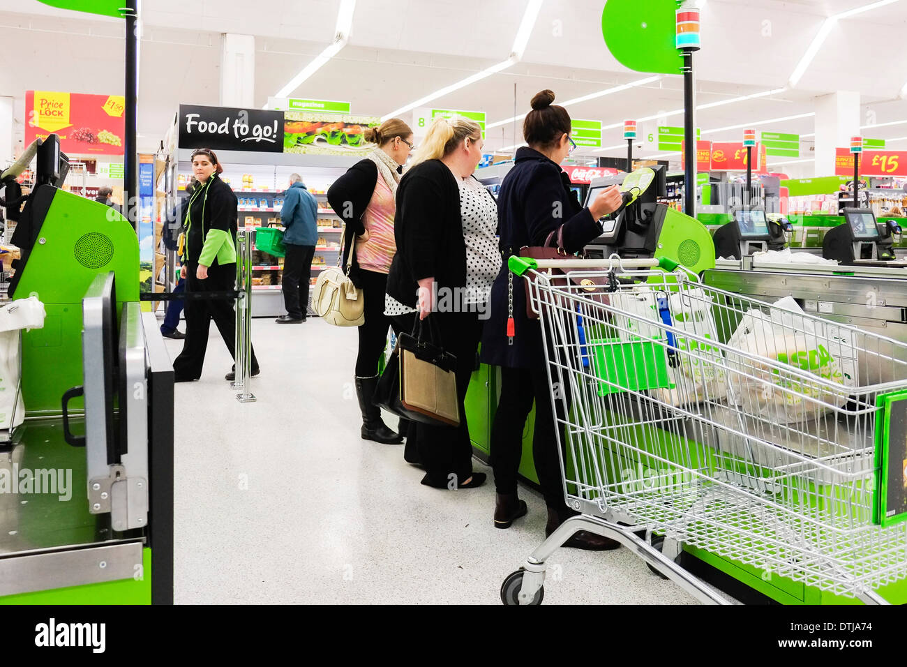 Customers queuing to pay at a self service till in an Asda supermarket. Stock Photo