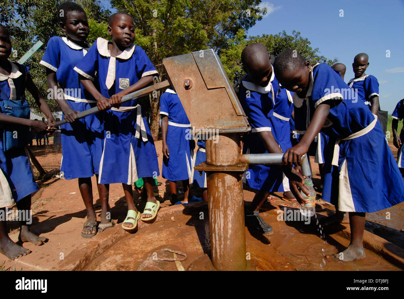 UGANDA Kitgum, girls school of catholic church, girls in blue school uniform fetch drinking water from hand pump set Stock Photo