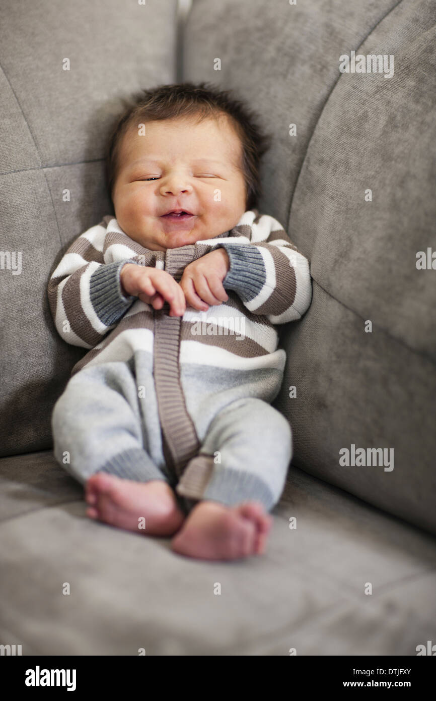 A baby propped up in the corner of a sofa  Philadelphia Pennsylvania USA Stock Photo