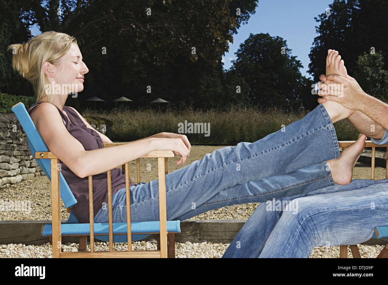 A woman seated with her legs outstretched having a foot massage England