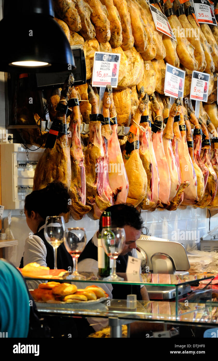 Madrid, Spain. Mercado de San Miguel (covered ironwork market - 1916) Whole hams / Jamon Iberico on sale - wineglasses on bar Stock Photo