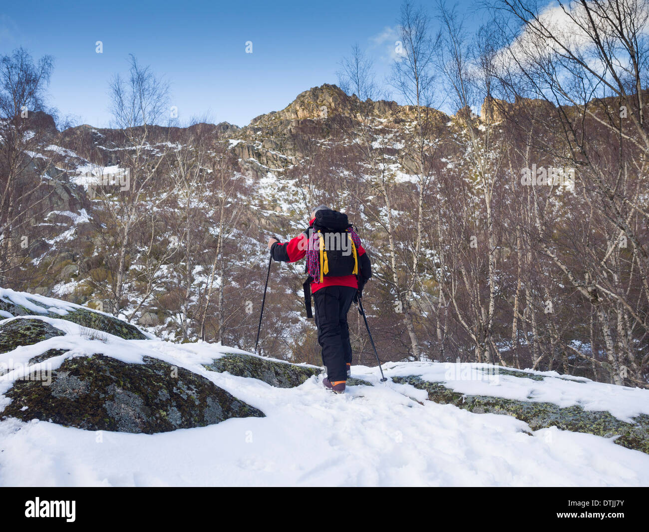 Hiker climbing a mountain covered in snow in the Winter Stock Photo