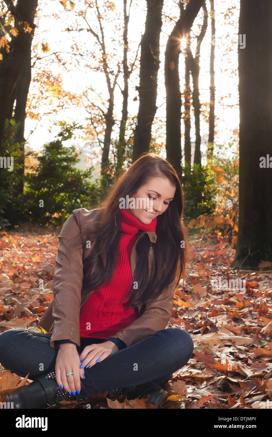 Happy brunette is having a nice time in the park while it's autumn Stock Photo