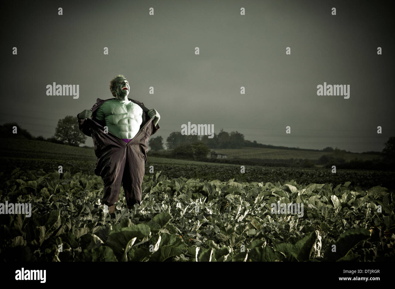 SUPERHERO COSTUME MAN STANDING IN A FIELD Stock Photo