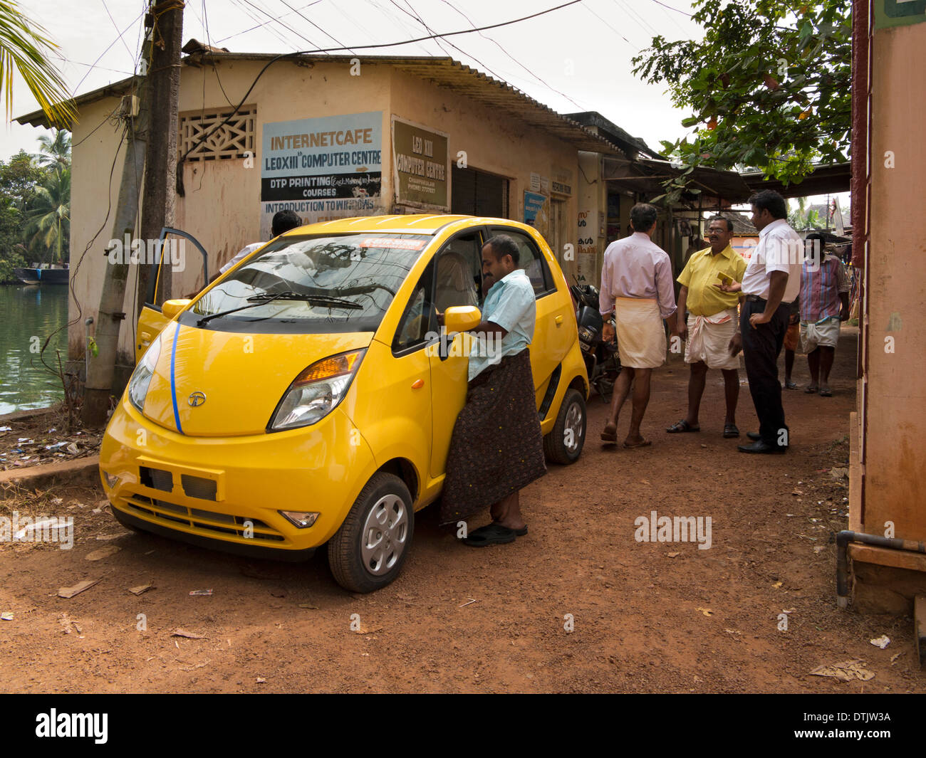 India, Kerala, backwaters, yellow Tata Nano car on riverbank Stock Photo