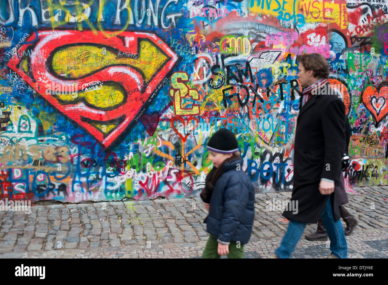 A girl walks past the John Lennon Wall in Prague center . The John Lennon Wall is a wall, which once was one most of which could Stock Photo