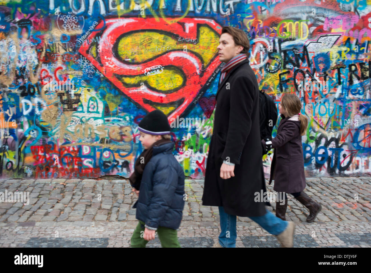 A girl walks past the John Lennon Wall in Prague center . The John Lennon Wall is a wall, which once was one most of which could Stock Photo