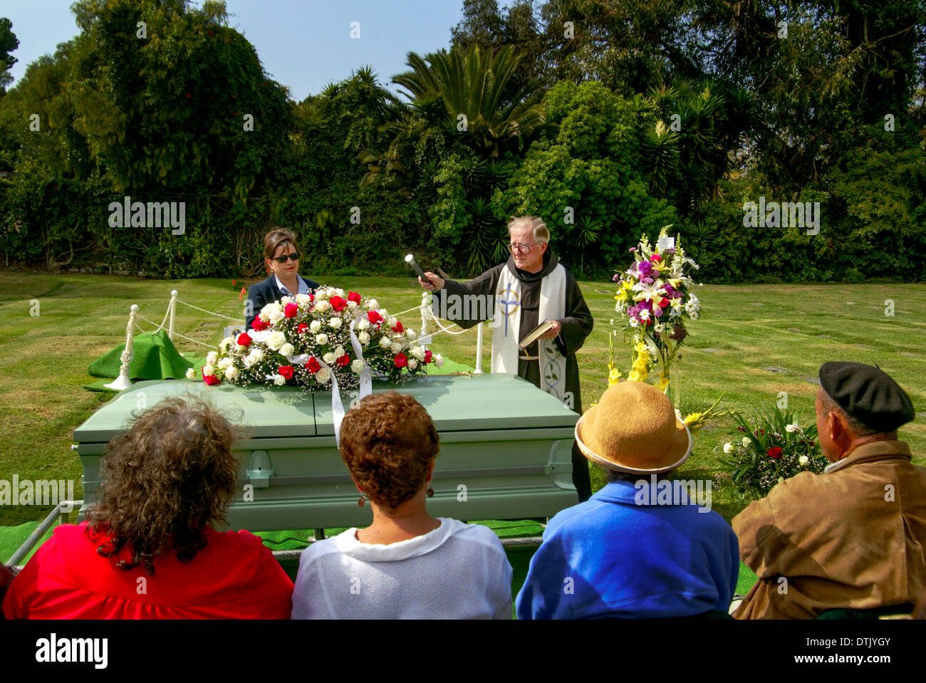 A robed Franciscan priest sprinkles holy water as he officiates at a