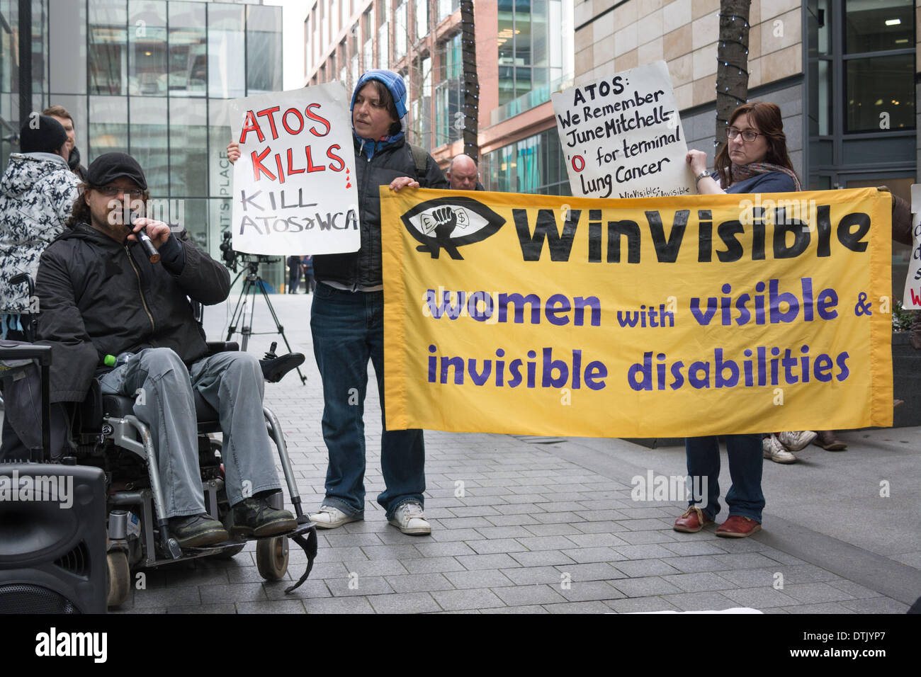 ATOS headquarters, London, UK, 19th February, 2014. An activist speaks as people gather outside ATOS head office in London to protest the company’s implementation of Work Capability Assessments. Protesters say that ATOS workers with little or no medical knowledge make poor decisions which lead to people losing their sickness benefits, and demand that a qualified medical doctor, ideally the GP who regularly sees and treats the sick or disabled person in question, is the only person able to decide if an individual is fit for work. Credit:  Patricia Phillips/Alamy Live News Stock Photo