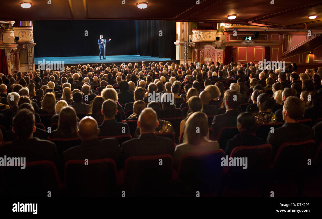 Audience watching performer on stage in theater Stock Photo