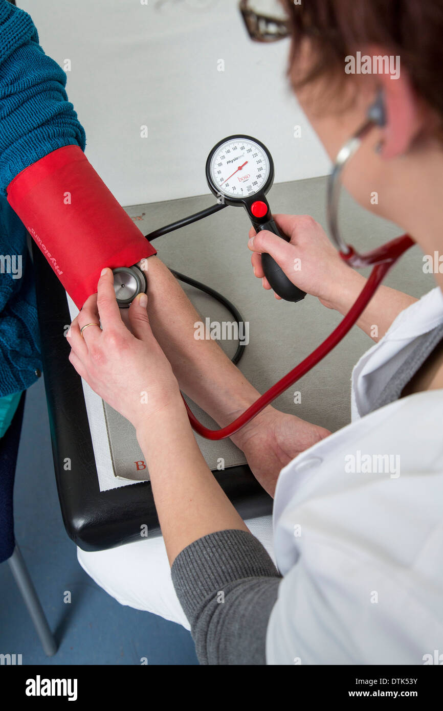 Doctors office. An assistant checks the blood pressure of a female patient. Stock Photo