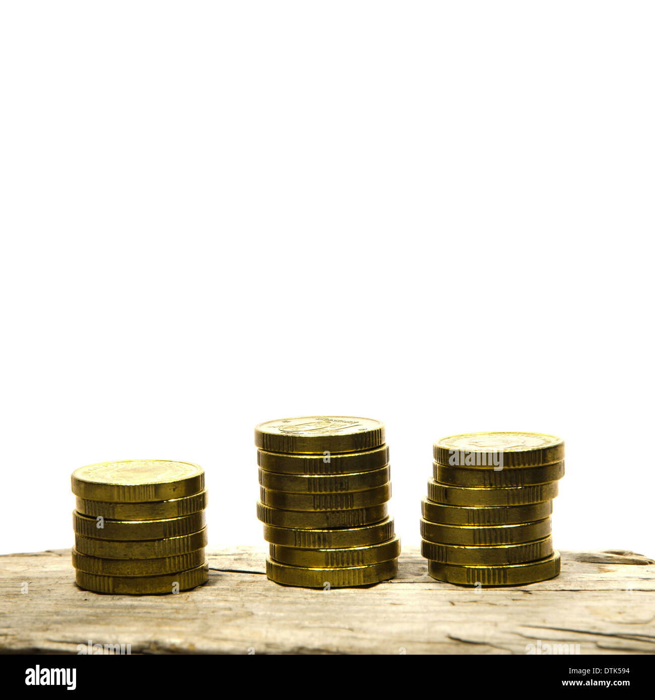 Piles of golden coins at wooden surface isolated on white Stock Photo