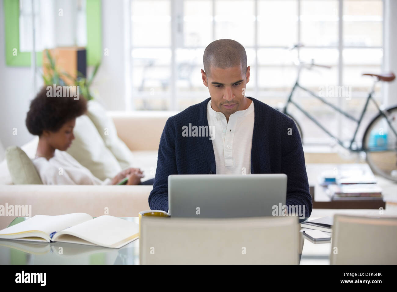 Man using laptop at desk in living room Stock Photo
