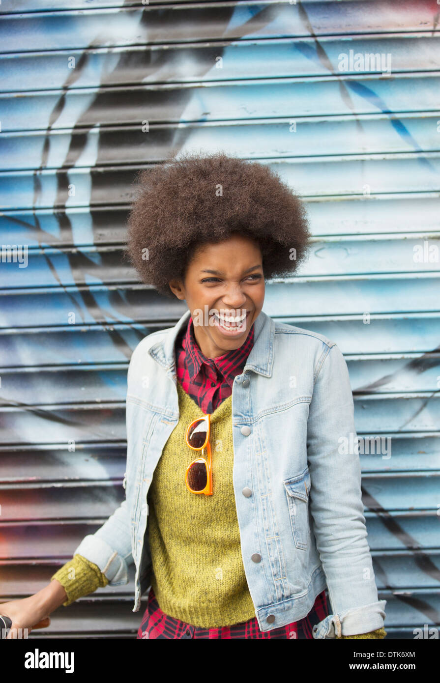 Woman laughing in front of graffiti wall Stock Photo