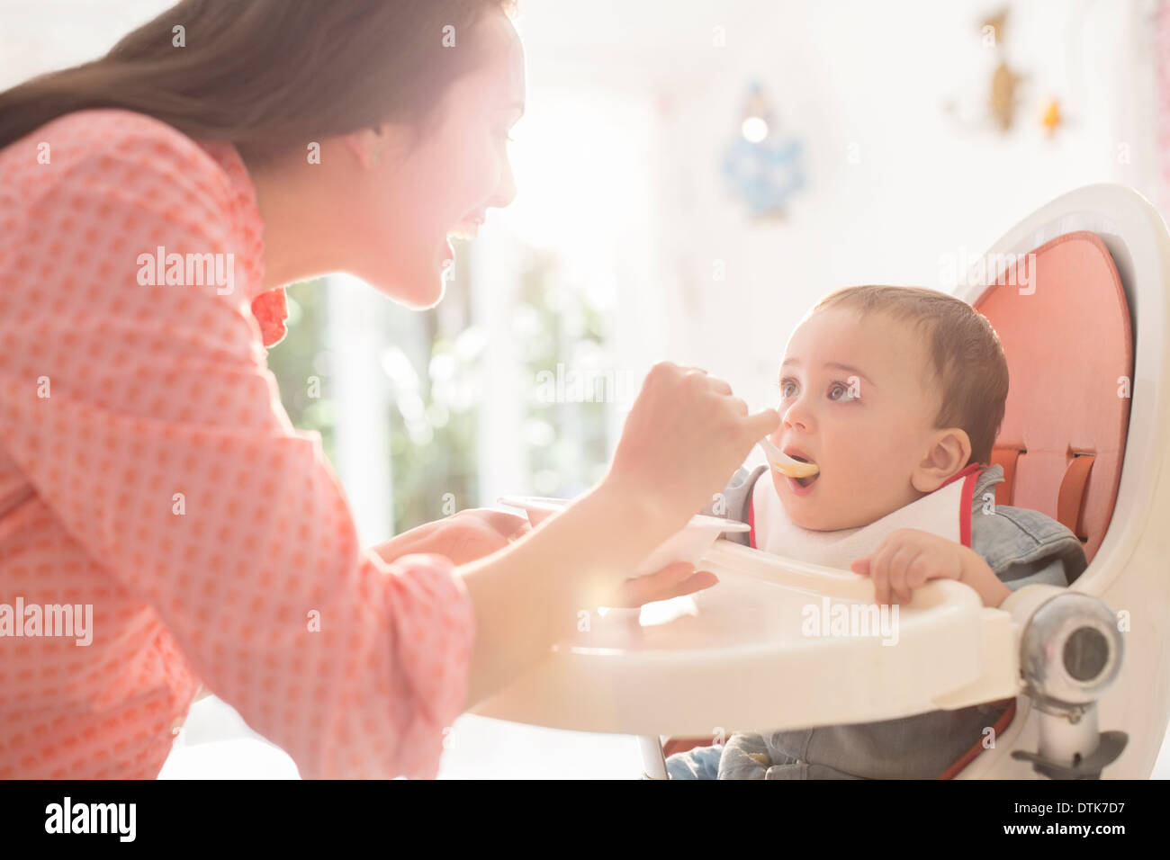 Mother feeding baby boy in high chair Stock Photo