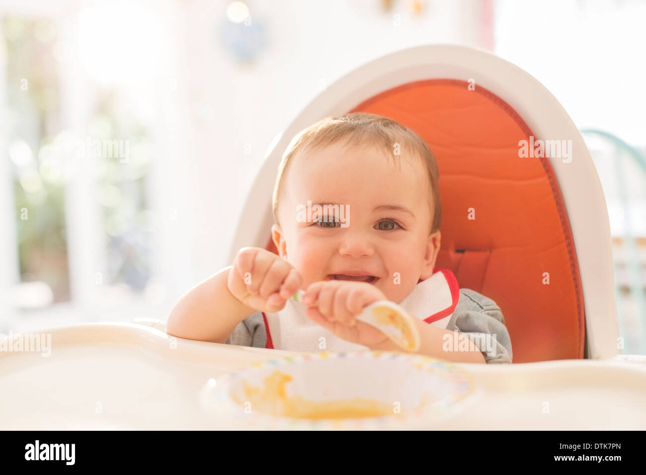 Baby boy eating in high chair Stock Photo Alamy
