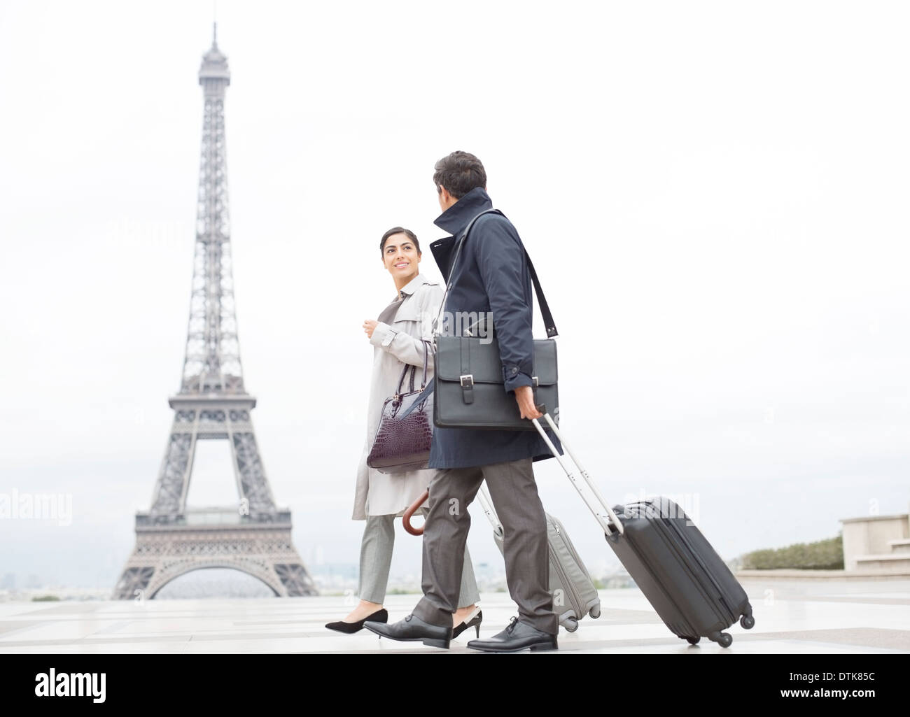 Business people with suitcases passing by Eiffel Tower, Paris, France