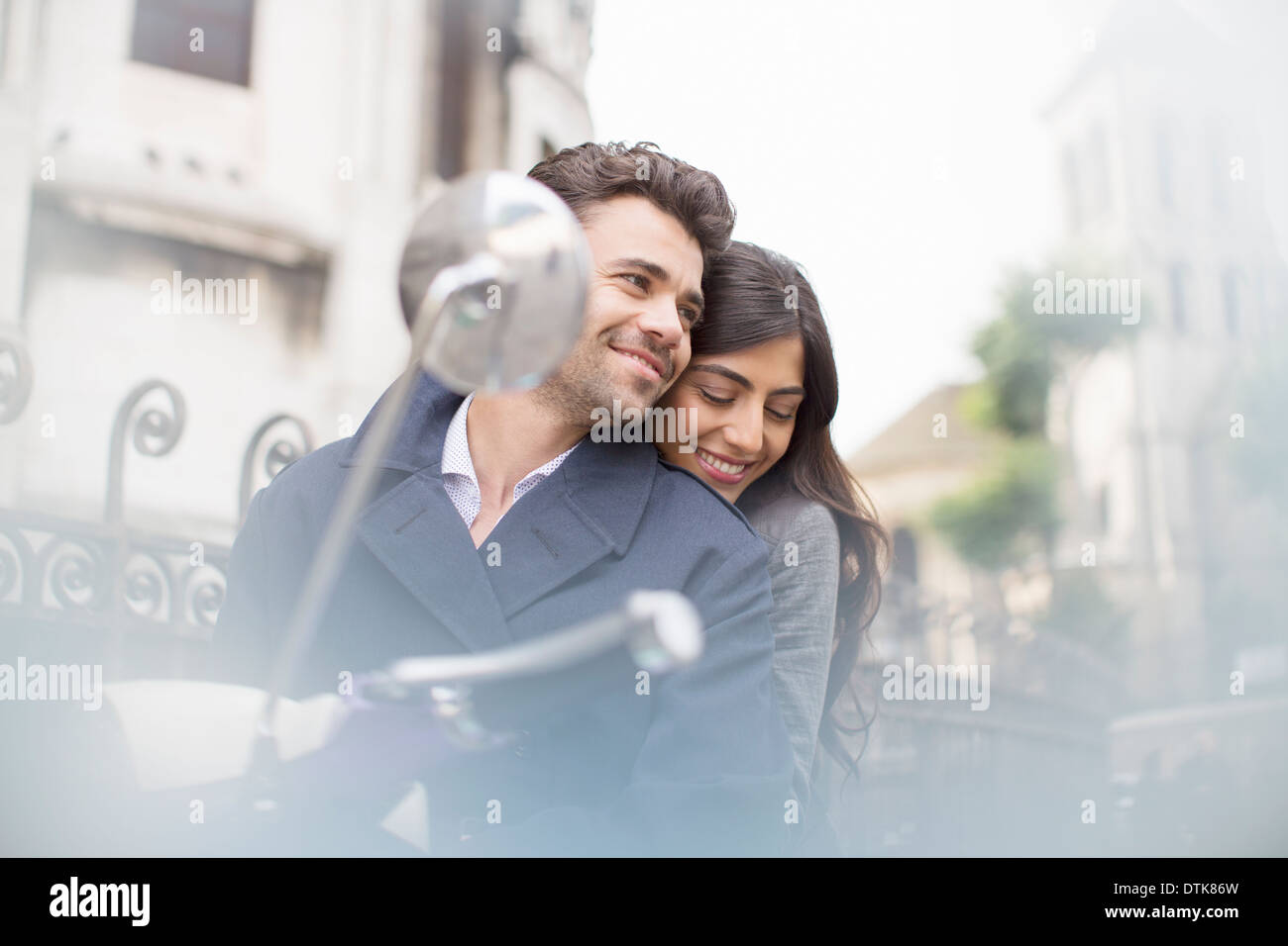 Couple sitting on scooter in city Stock Photo