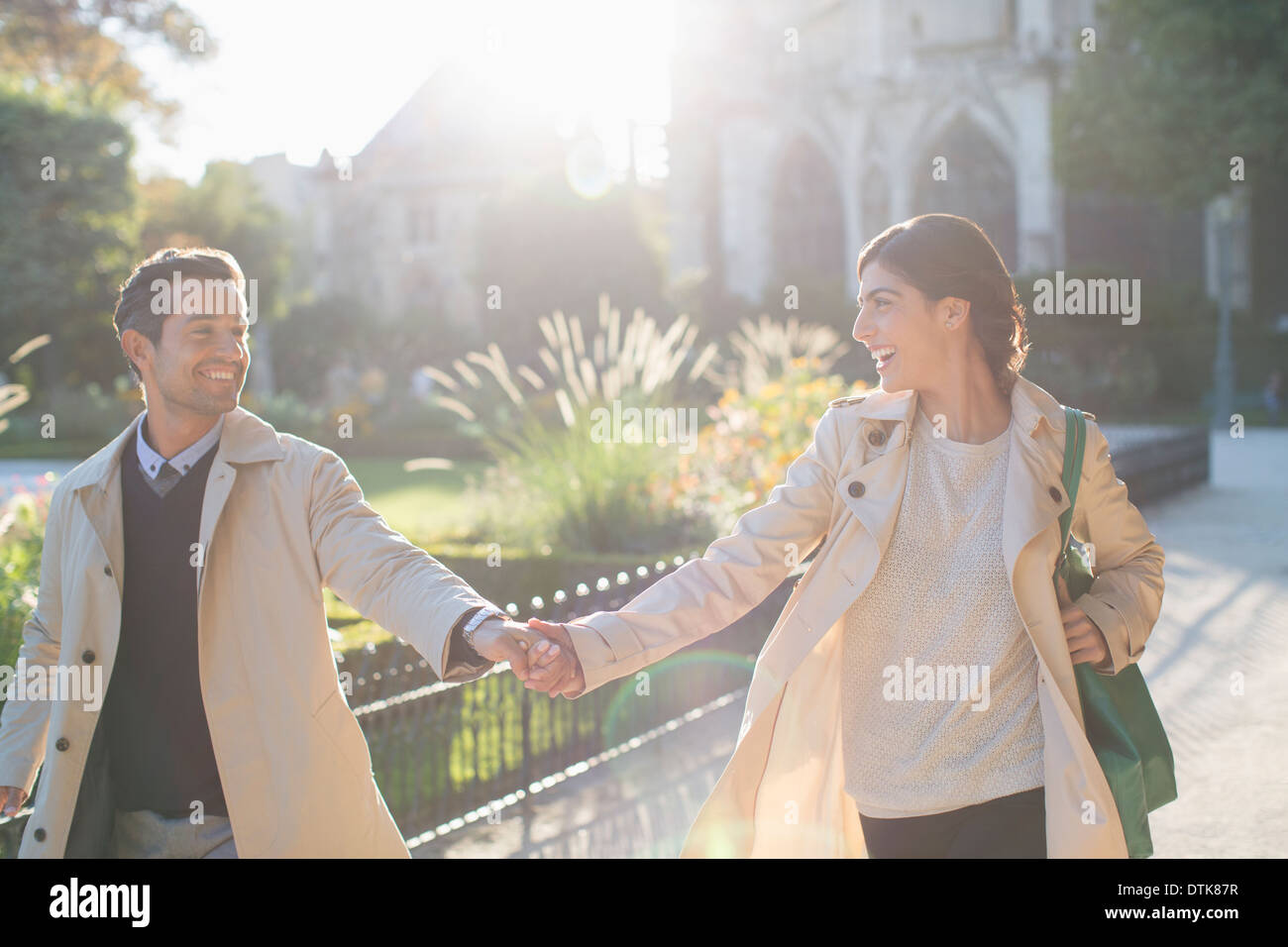 Couple holding hands in urban park Stock Photo - Alamy