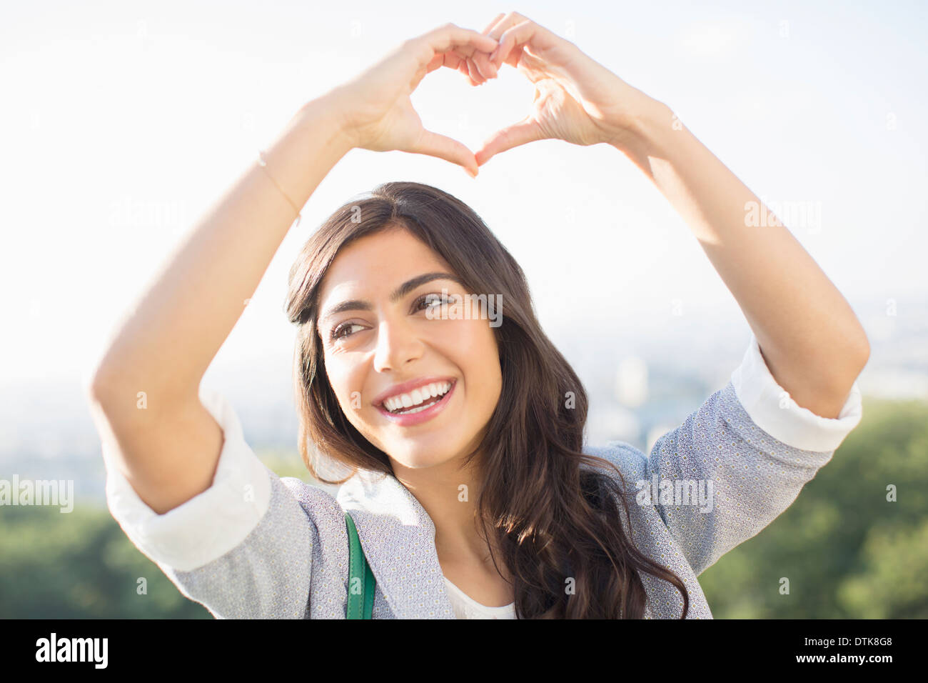 Woman making heart-shape with hands outdoors Stock Photo