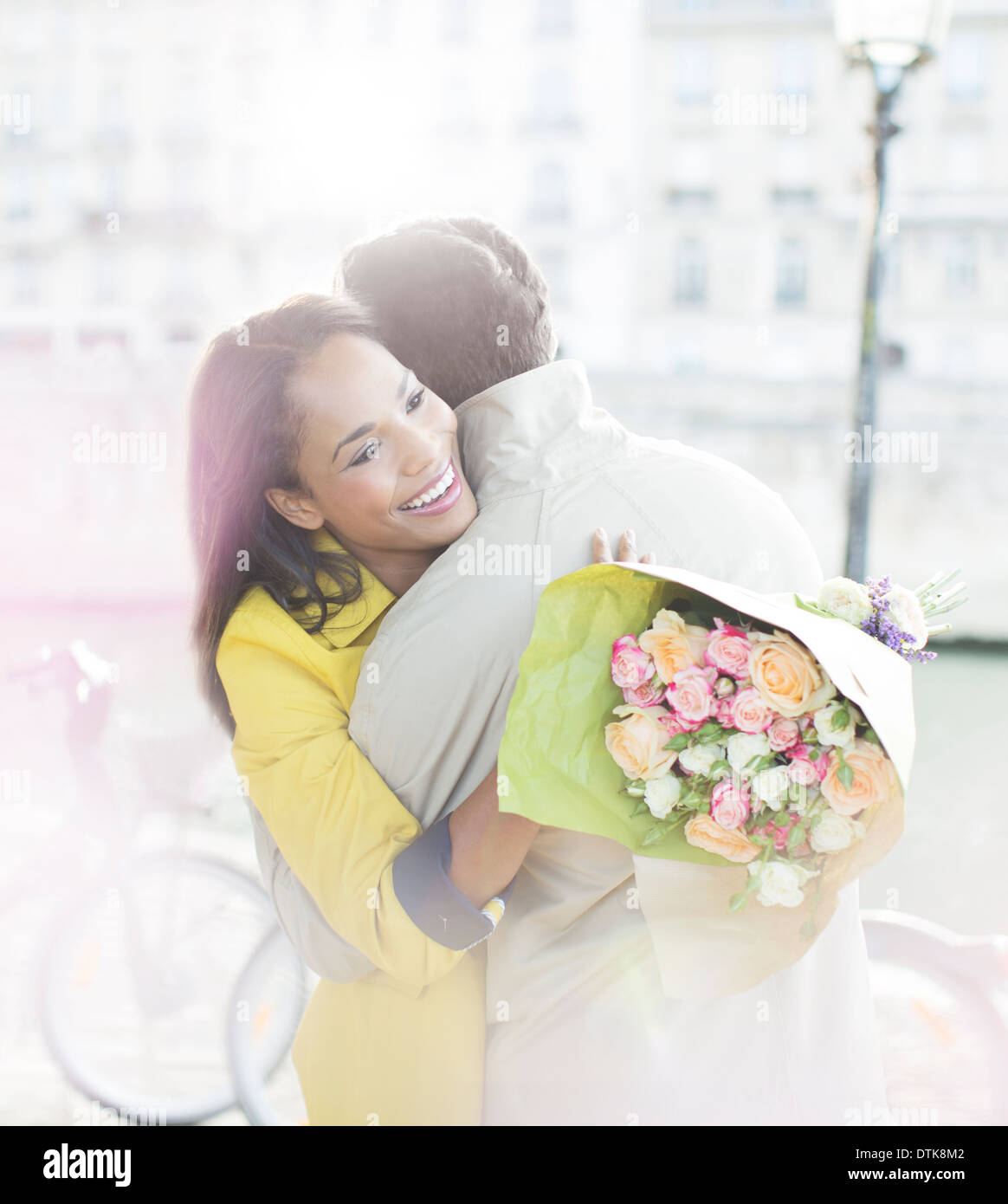 Couple with bouquet of flowers hugging along Seine River, Paris, France Stock Photo