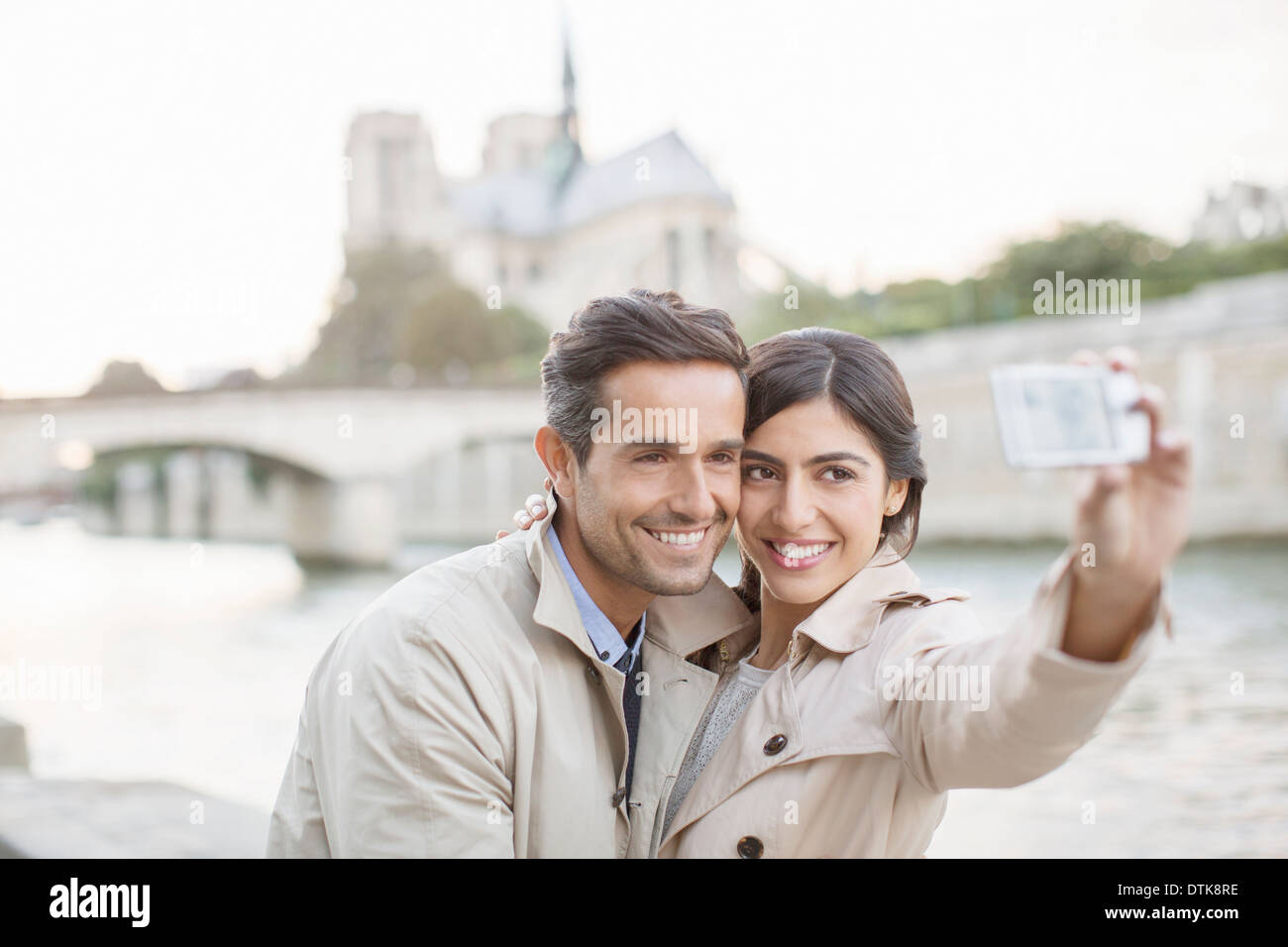 Couple taking self-portrait along Seine River near Notre Dame Cathedral, Paris, France Stock Photo