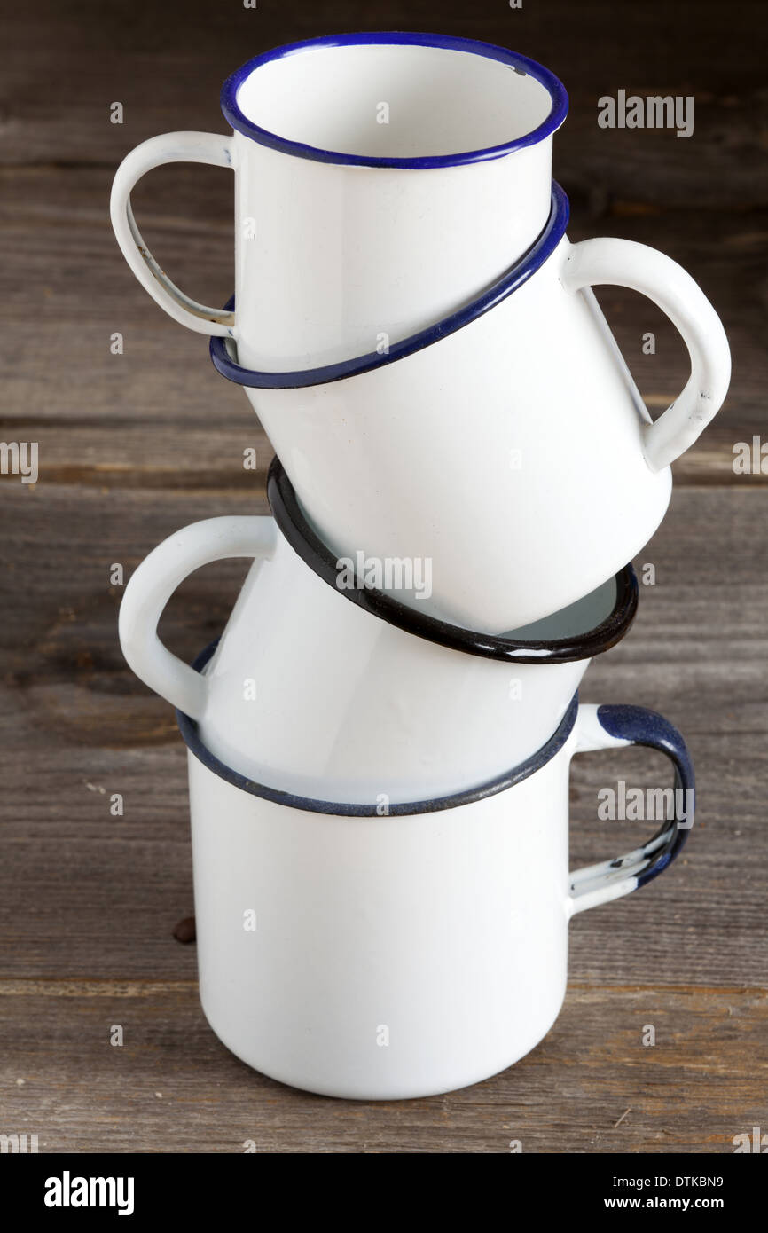 Four stacked Enamel coffee cup on rustic wooden background with copy space on the mugs Stock Photo