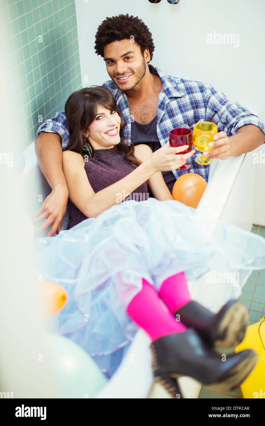 Couple toasting each other in bathtub at party Stock Photo