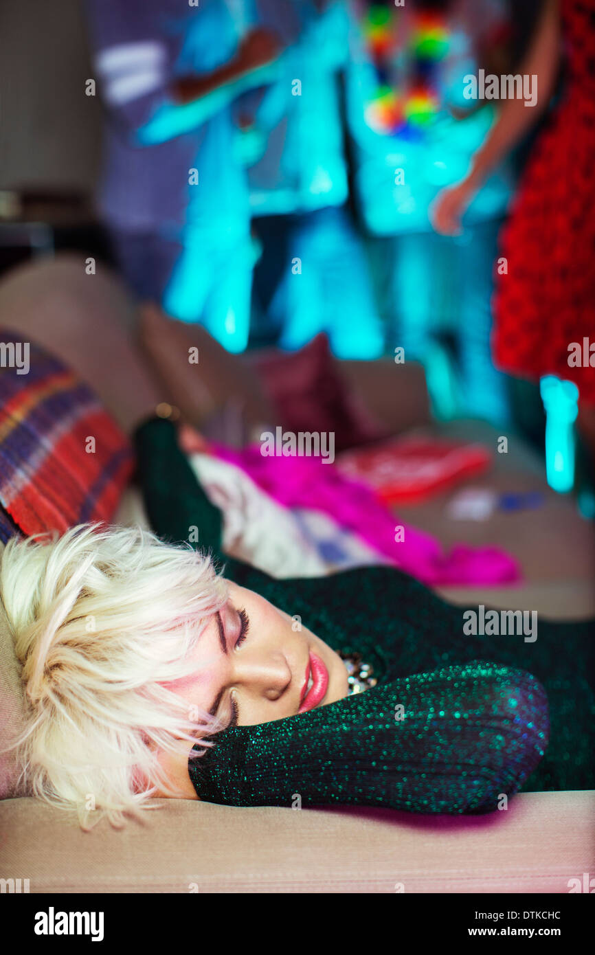 Woman sleeping on sofa at party Stock Photo