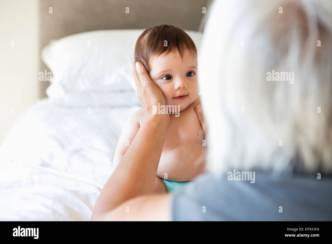 Woman holding granddaughter on bed Stock Photo