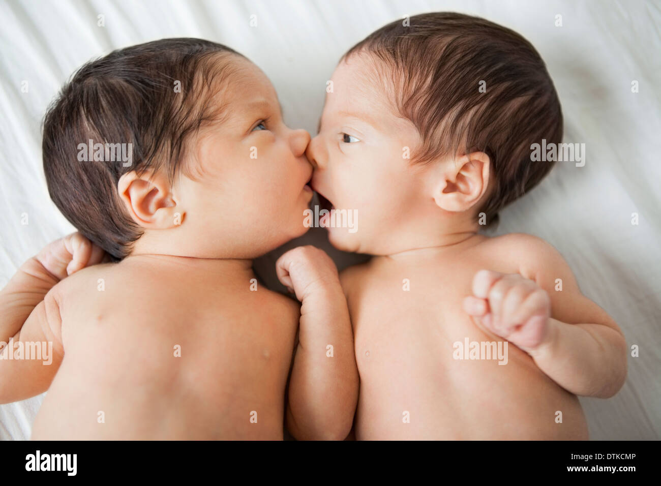 Twin baby girls kissing on bed Stock Photo