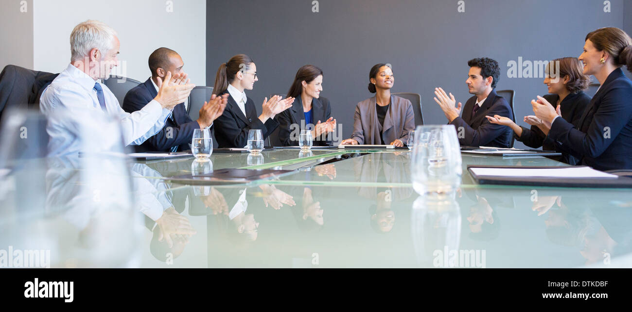 Business people applauding colleague in meeting Stock Photo