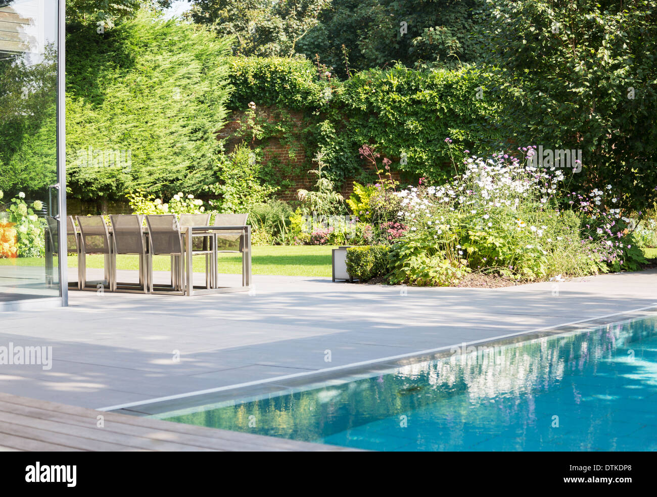 Table and chairs by outdoor swimming pool Stock Photo