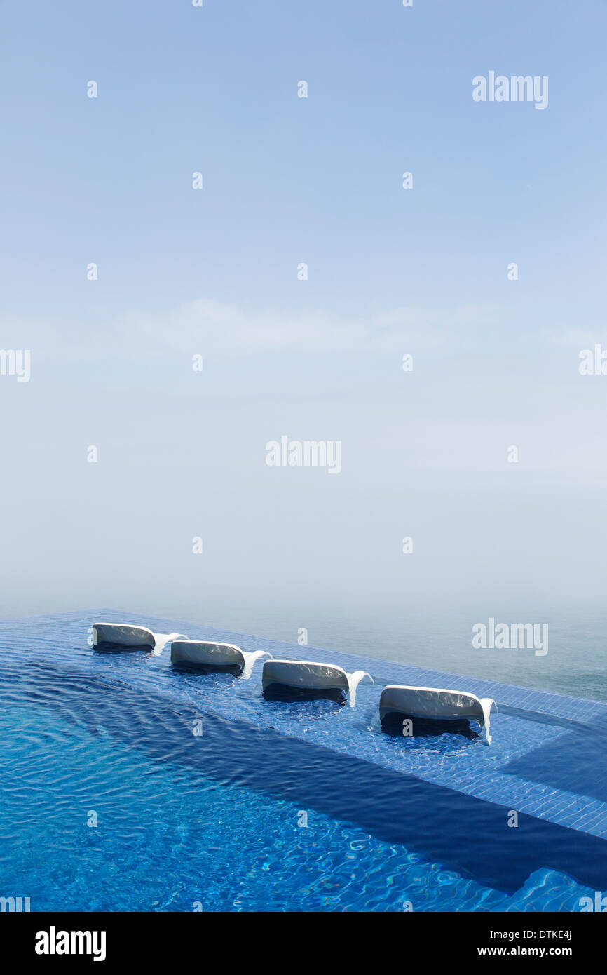 Lawn chairs in infinity pool overlooking ocean Stock Photo Alamy