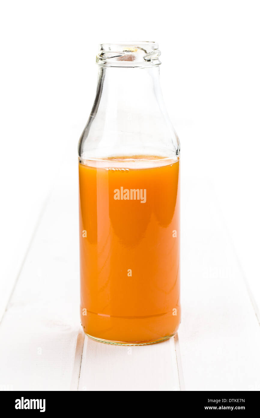 bottle of carrot juice on white wooden background Stock Photo