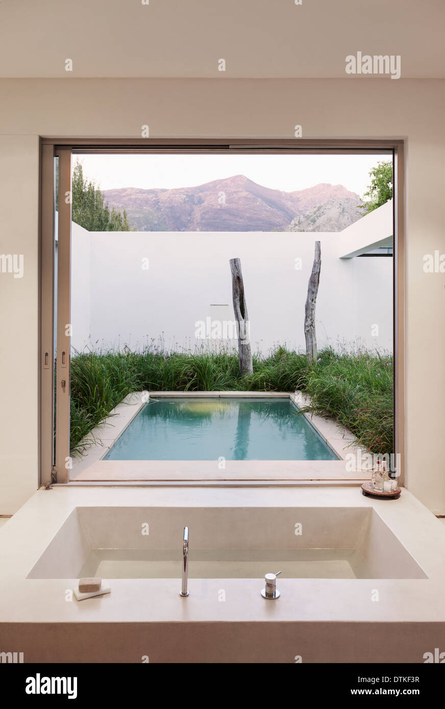 Modern bathroom overlooking swimming pool and mountains Stock Photo